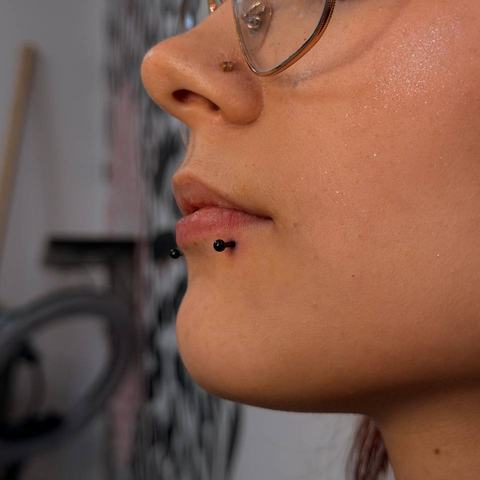 Facial piercing combination: a lip piercing paired with a nose piercing, creating a balanced and expressive look.