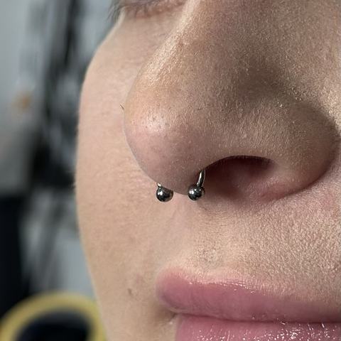 Septum - stilingas nosies pertvaros vėrimas, suteikiantis veidui aiškų ir subalansuotą akcentą. Tikslus atlikimas, sterilios sąlygos ir dėmesys ramiam gijimo procesui.