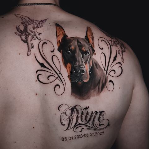 A large upper back tattoo with a dark central figure, flowing ornamental lines and red accents