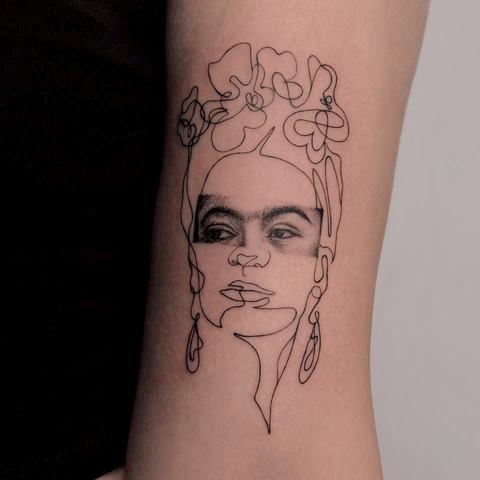 A delicate fine line portrait tattoo with ornamental details and an expressive minimalist composition.