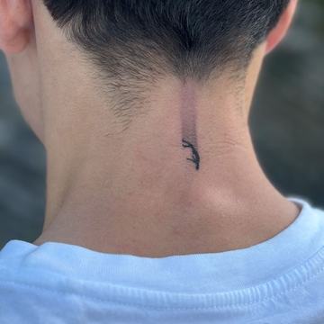 Maža juodo rašalo tatuiruotė ant sprando: minimalistinis blackwork simbolis po plaukų linija—pavyzdys mažam formatui matomoje vietoje.