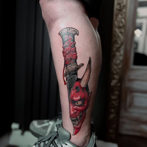 A bold calf tattoo combining a dark illustrative portrait with vivid red tones, layered details, and a strong vertical flow.