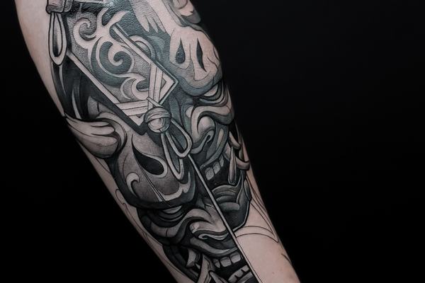 Juodai pilka kaukės tatuiruotė ant dilbio