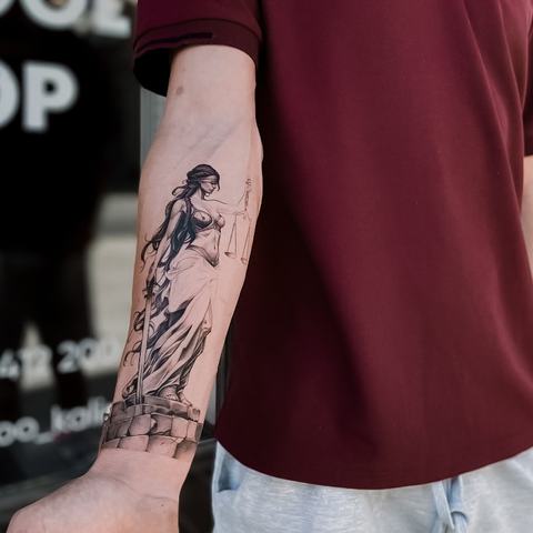 A detailed blackwork forearm tattoo with a dynamic figure and expressive linework