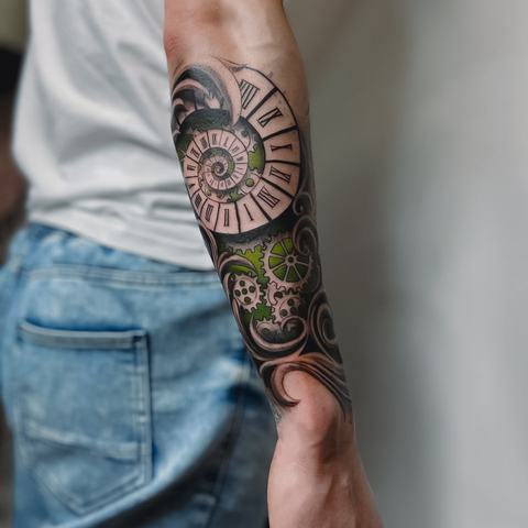 A bold forearm tattoo with geometric patterns, intricate blackwork and subtle green details