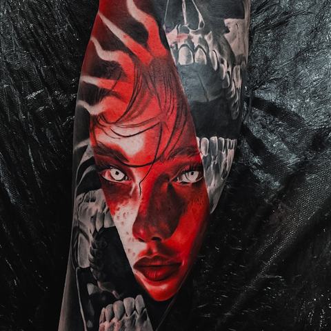 A dramatic red and black sleeve tattoo featuring a female portrait, skull imagery and bold graphic details