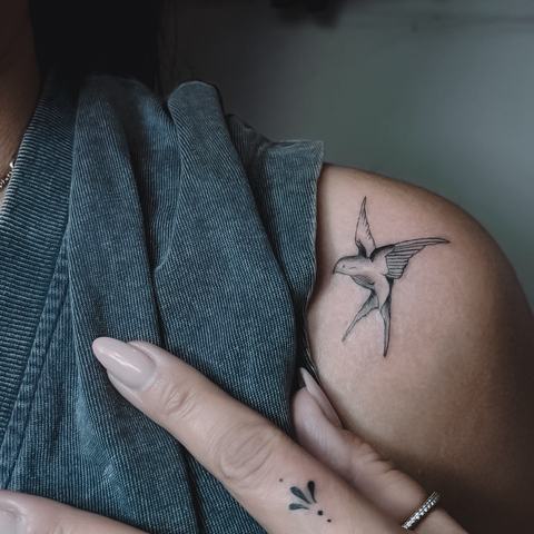 Subtili minimalistinė tatuiruotė ant šlaunies, sukurta plonomis linijomis ir lengva, elegantiška kompozicija, natūraliai prisitaikančia prie kūno formų.