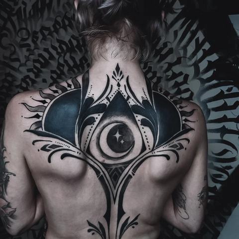 Ryški juodo rašalo nugaros tatuiruotė su simetriška ornamentine kompozicija, centriniu akies motyvu ir aštriomis grafinėmis linijomis, išryškinančiomis pečių bei nugaros formą.