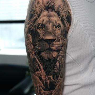 Detailed lion tattoo on upper arm with dark shading