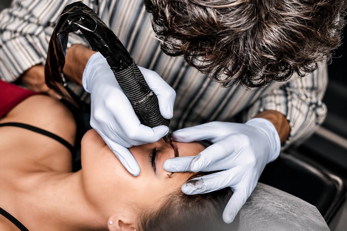 Permanent makeup specialist working on a model's eyebrow