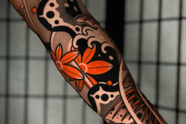 Japanese arm tattoo with orange flower and black ornamental pattern