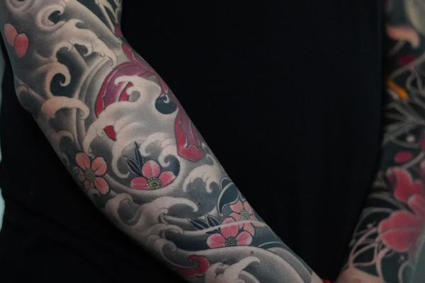 Japanese forearm tattoo with waves, flowers and clouds