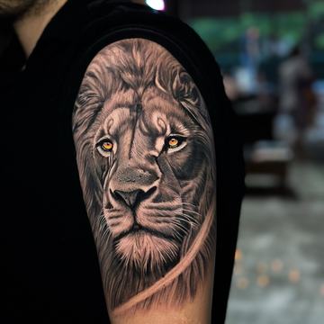 Realistic lion portrait tattoo with bright eye accents