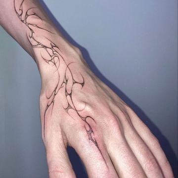 Fine black line tattoo running from hand to wrist